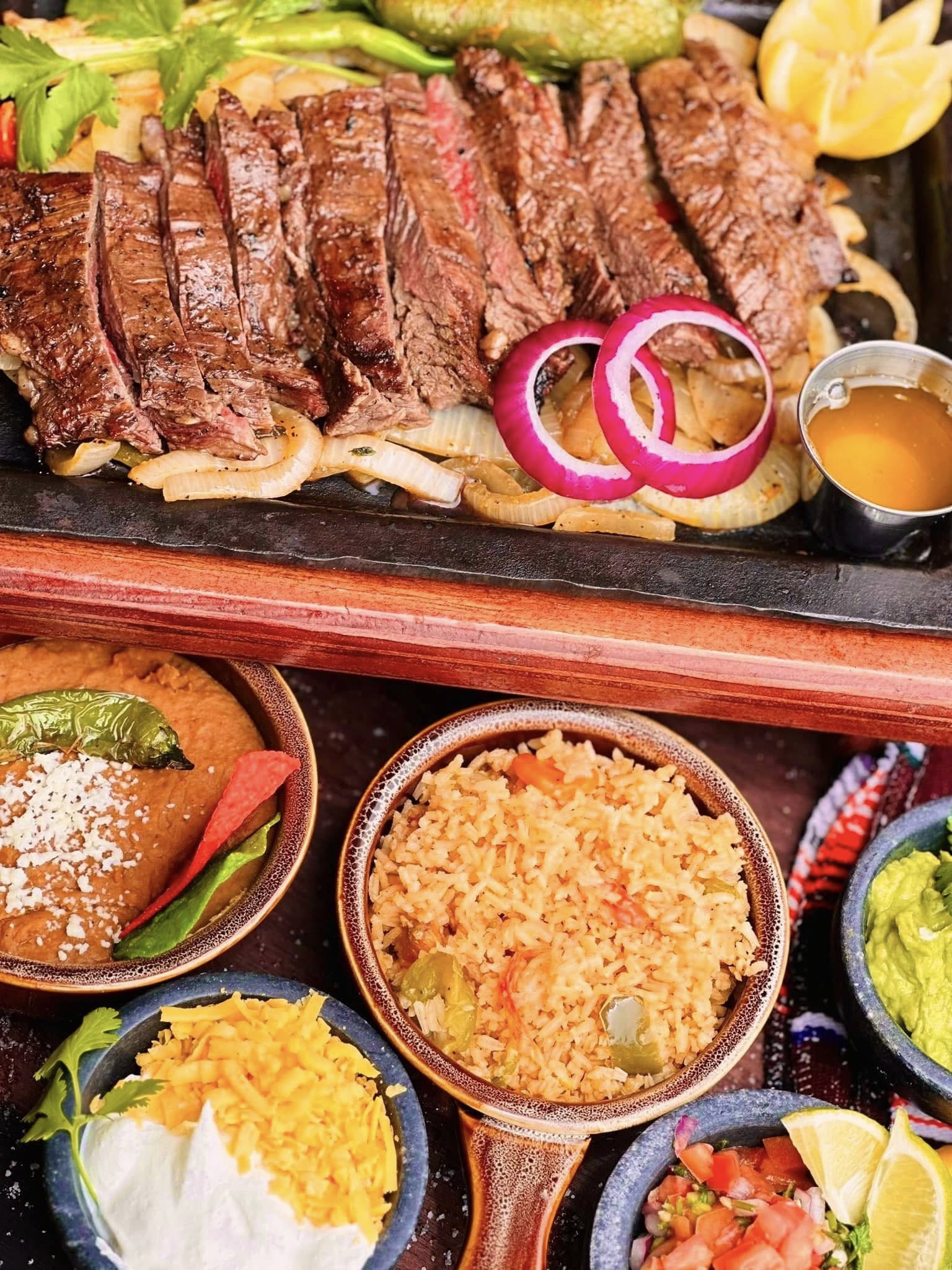 Sliced grilled steak with rice, beans and accompaniments
