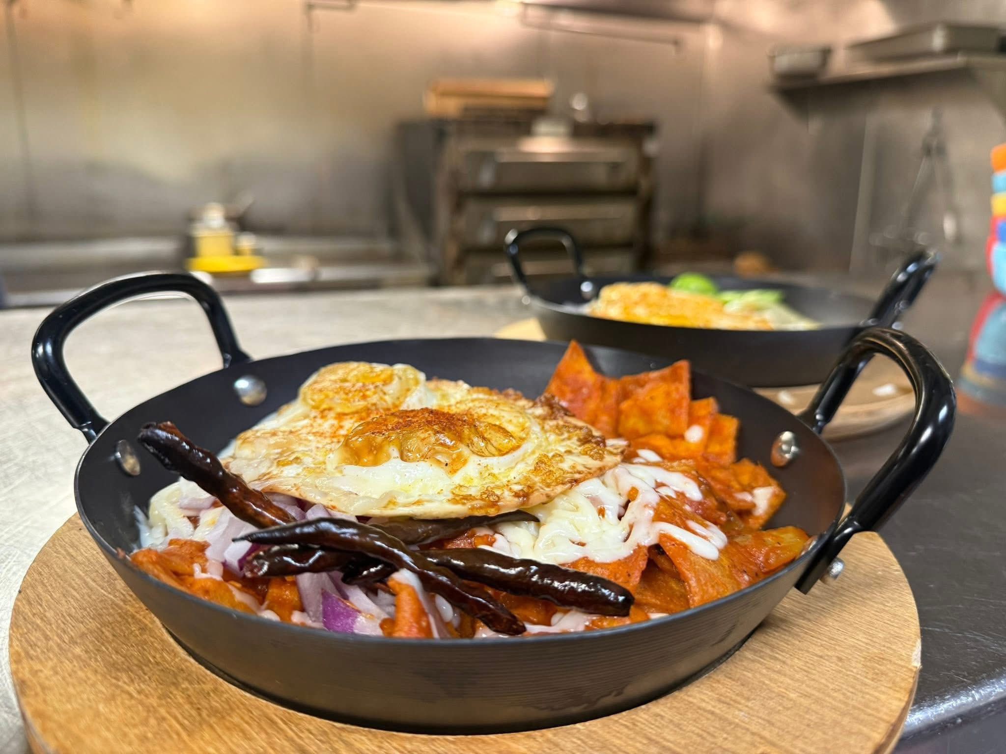 Chilaquiles topped with a fried egg in a black pan