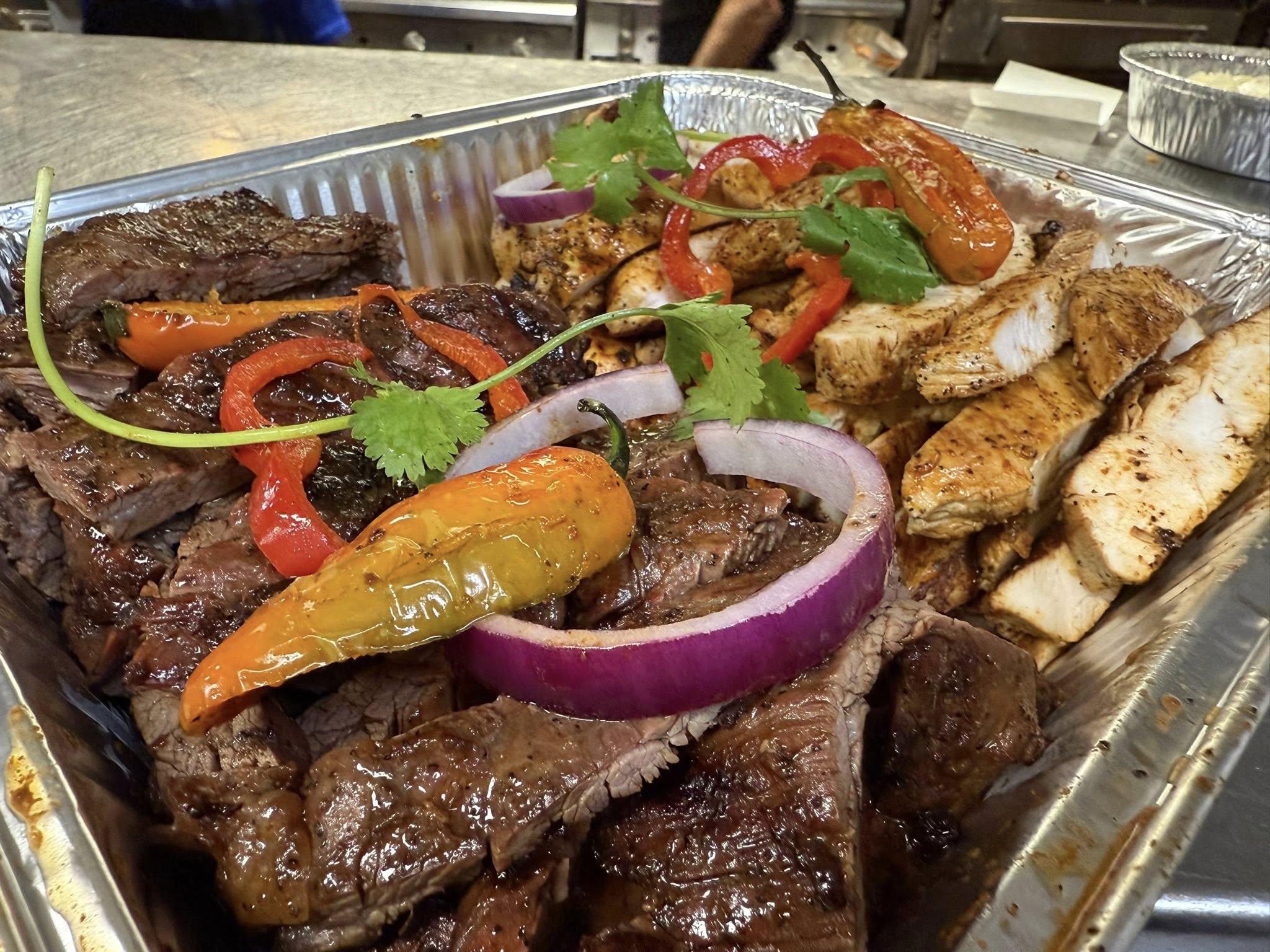 Mixed catering tray with grilled steak, chicken, and peppers