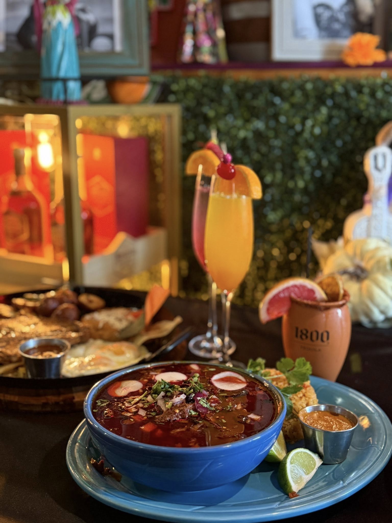 Bowl of birria served with a tall mimosa cocktail