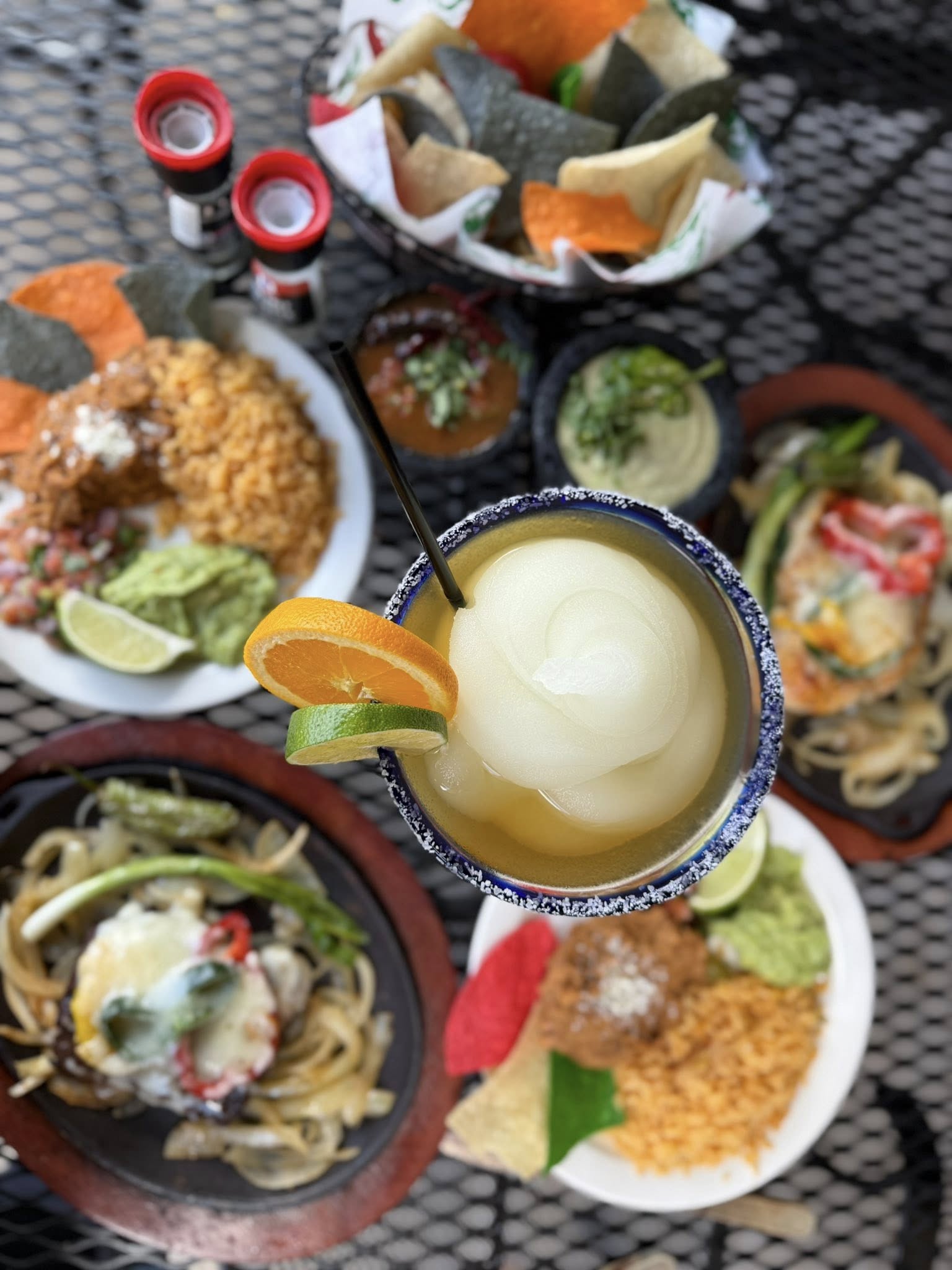 Overhead view of a margarita with a full table of food