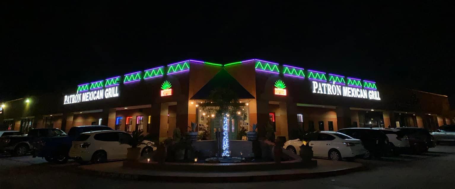 Patron Mexican Grill at night, exterior with neon signs and lit fountain